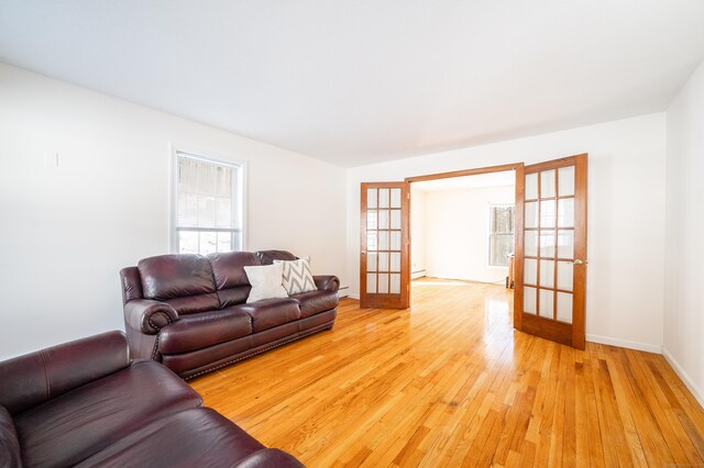 living room with a baseboard radiator, light wood-type flooring, and french doors