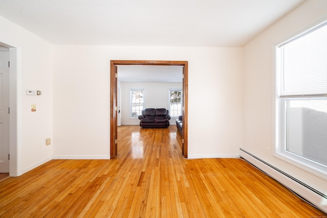 unfurnished room with a baseboard heating unit and light wood-type flooring