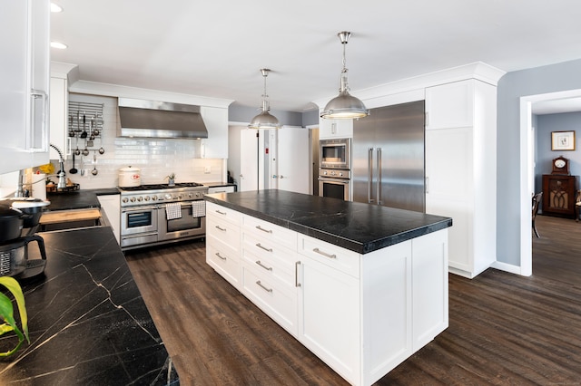 kitchen featuring white cabinetry, wall chimney exhaust hood, built in appliances, and a center island