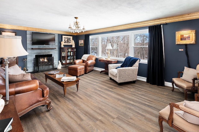 living room with a notable chandelier, ornamental molding, hardwood / wood-style floors, and a large fireplace