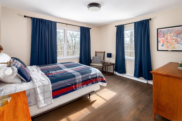 bedroom with multiple windows and dark wood-type flooring