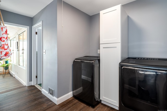 laundry room with cabinets, dark hardwood / wood-style flooring, and washer and clothes dryer