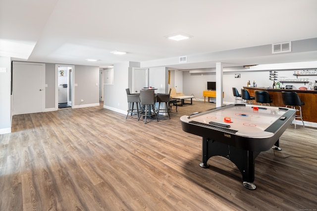 game room with wood-type flooring and bar