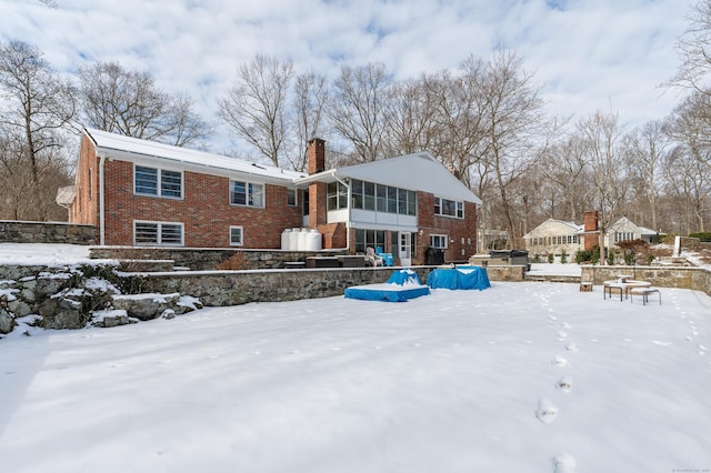 snow covered rear of property featuring a pool