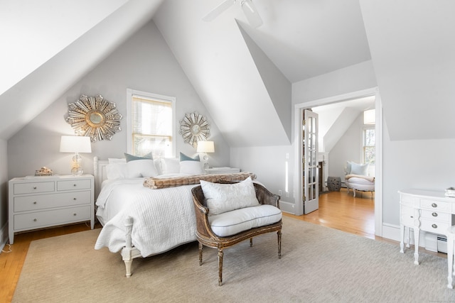 bedroom featuring vaulted ceiling, light hardwood / wood-style floors, and multiple windows