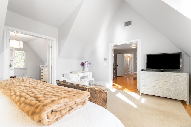 bedroom featuring high vaulted ceiling and light hardwood / wood-style floors