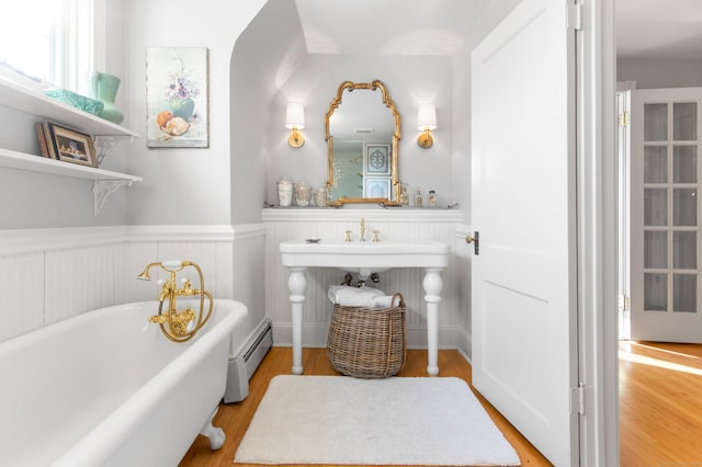 bathroom featuring a washtub, hardwood / wood-style flooring, and baseboard heating