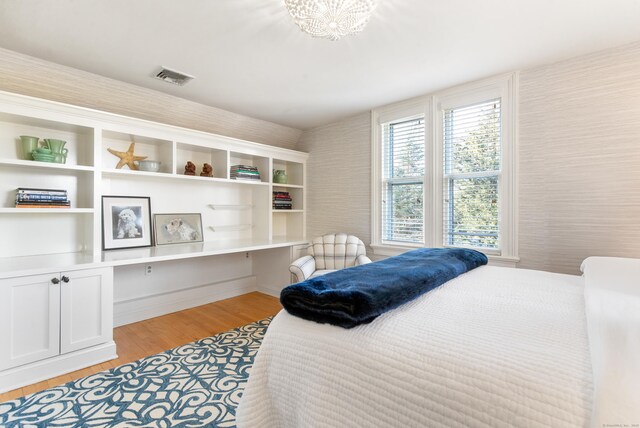 bedroom with built in desk and light wood-type flooring