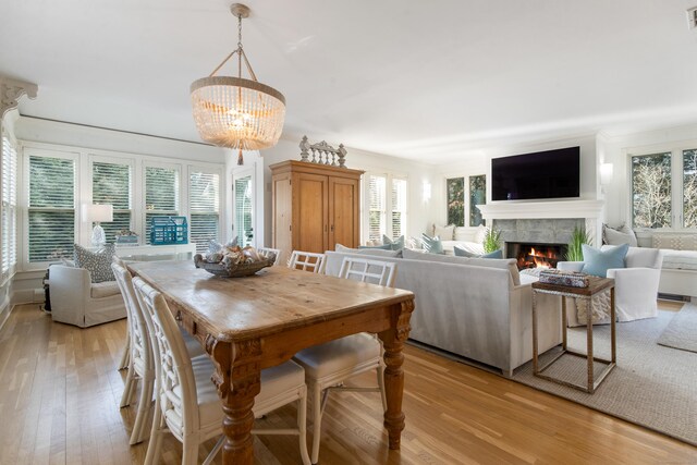 dining area with light hardwood / wood-style flooring, ornamental molding, and a chandelier