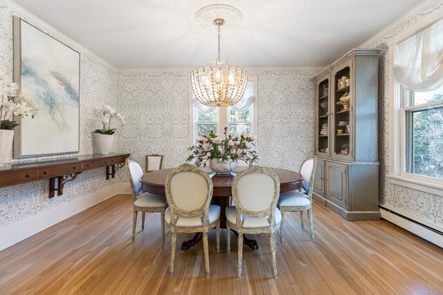 dining space featuring a baseboard heating unit, a notable chandelier, light hardwood / wood-style flooring, and ornamental molding