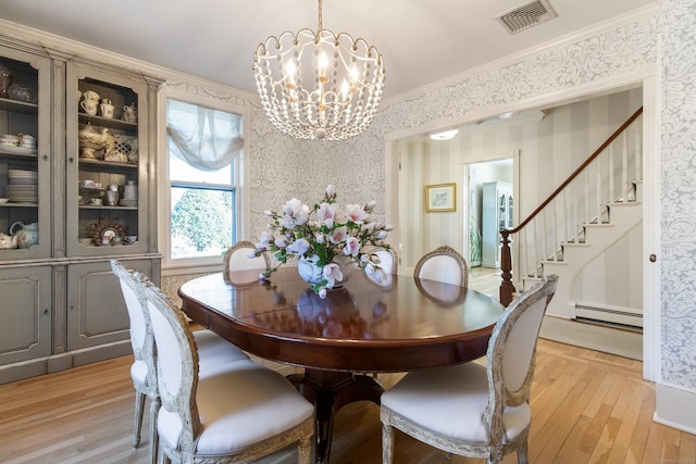 dining area with a baseboard radiator, ornamental molding, a chandelier, and light hardwood / wood-style floors