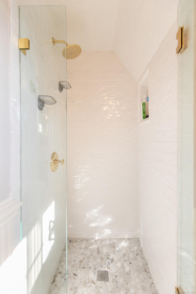 bathroom with lofted ceiling and tiled shower