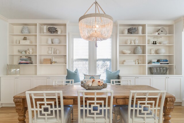 dining space featuring ornamental molding, a chandelier, and light hardwood / wood-style flooring