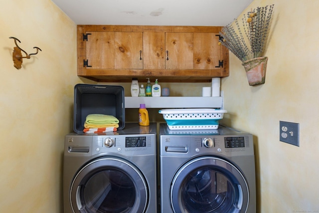 clothes washing area with washer and clothes dryer and cabinets