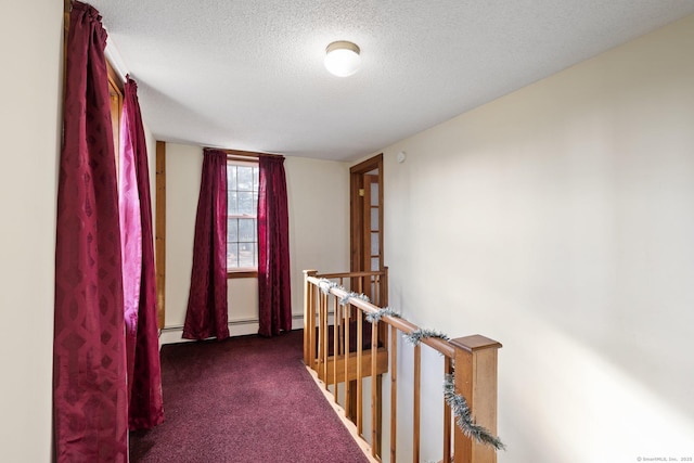 hallway with a baseboard radiator, a textured ceiling, and dark colored carpet