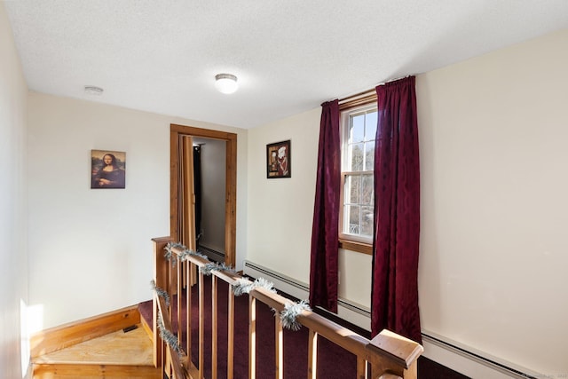 stairs with baseboard heating and a textured ceiling