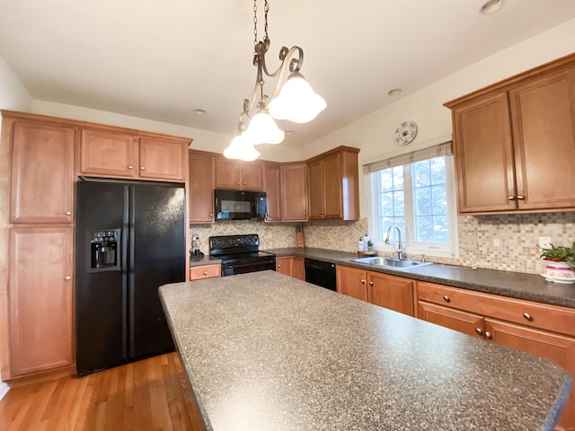 kitchen featuring sink, backsplash, hanging light fixtures, light hardwood / wood-style floors, and black appliances