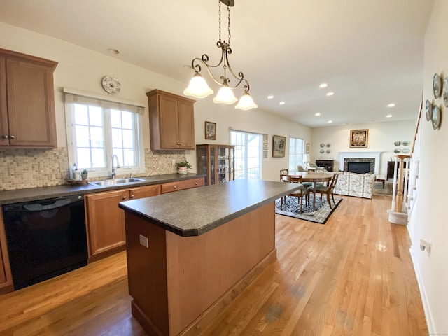 kitchen featuring decorative light fixtures, tasteful backsplash, black dishwasher, sink, and a center island