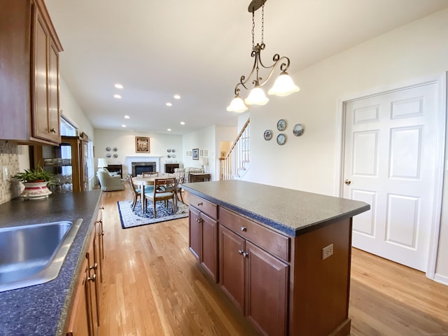 kitchen with hanging light fixtures, light wood-type flooring, sink, and a kitchen island