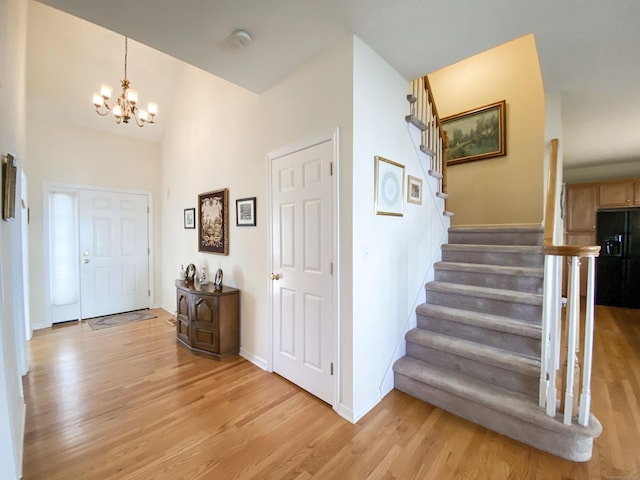 foyer with lofted ceiling, a chandelier, and light wood-type flooring