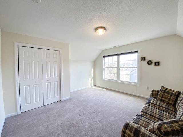 living area with light carpet, vaulted ceiling, and a textured ceiling