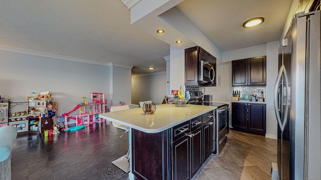 kitchen featuring dark brown cabinetry, a breakfast bar area, crown molding, appliances with stainless steel finishes, and backsplash