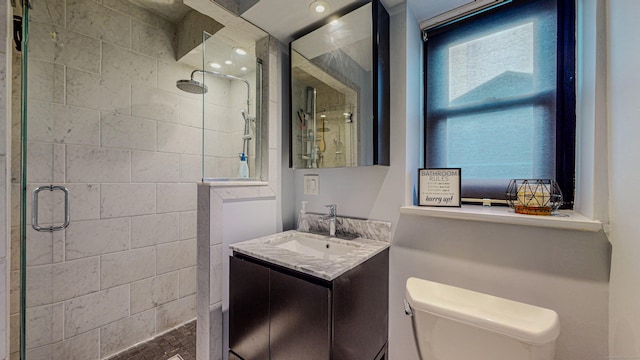 bathroom with a shower with door, vanity, and toilet