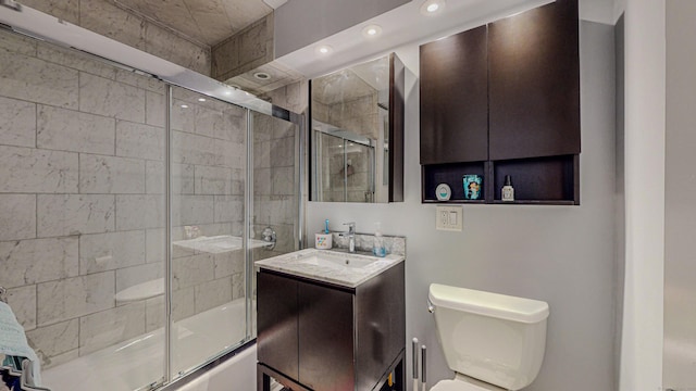 full bathroom featuring vanity, combined bath / shower with glass door, and toilet