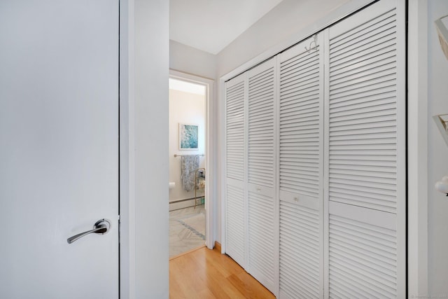 hallway with light hardwood / wood-style floors and a baseboard heating unit