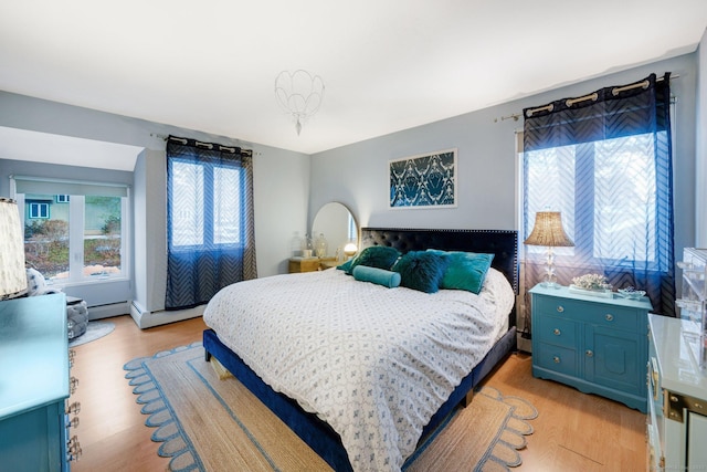 bedroom with a baseboard radiator, multiple windows, and light wood-type flooring