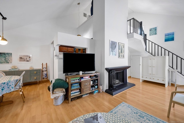 living room featuring high vaulted ceiling and light hardwood / wood-style flooring