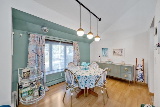 dining area with rail lighting, a baseboard radiator, vaulted ceiling, and light hardwood / wood-style flooring