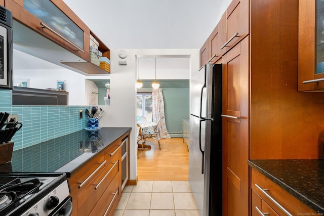 kitchen with light tile patterned flooring, appliances with stainless steel finishes, decorative light fixtures, tasteful backsplash, and dark stone countertops