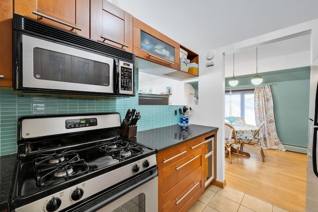 kitchen featuring tasteful backsplash, hanging light fixtures, light tile patterned floors, baseboard heating, and stainless steel appliances