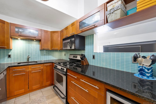 kitchen featuring sink, light tile patterned floors, dark stone countertops, stainless steel appliances, and tasteful backsplash