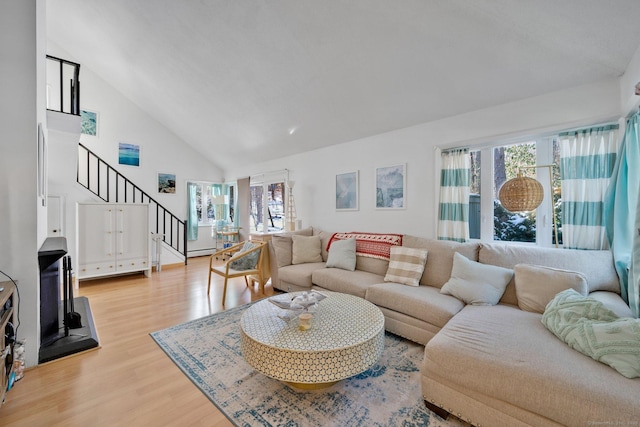 living room with light hardwood / wood-style flooring and high vaulted ceiling