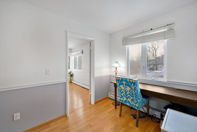 office area with built in desk, light wood-type flooring, and baseboard heating