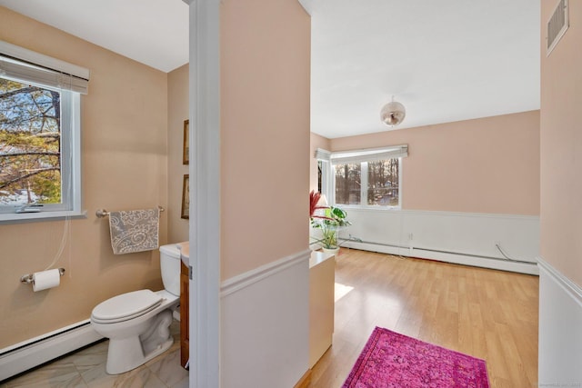 bathroom with a baseboard heating unit, wood-type flooring, and toilet