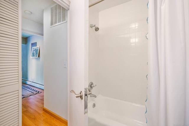 bathroom featuring hardwood / wood-style flooring, shower / bath combo, and baseboard heating