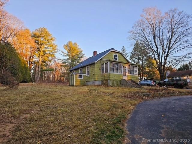 view of side of home with a chimney and a sunroom