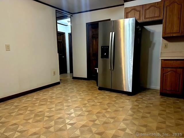 kitchen with baseboards, stainless steel refrigerator with ice dispenser, and light countertops