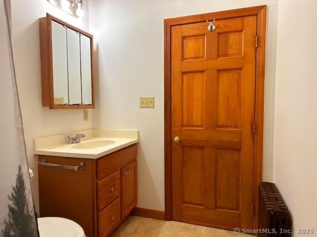 bathroom with vanity, toilet, radiator heating unit, and baseboards