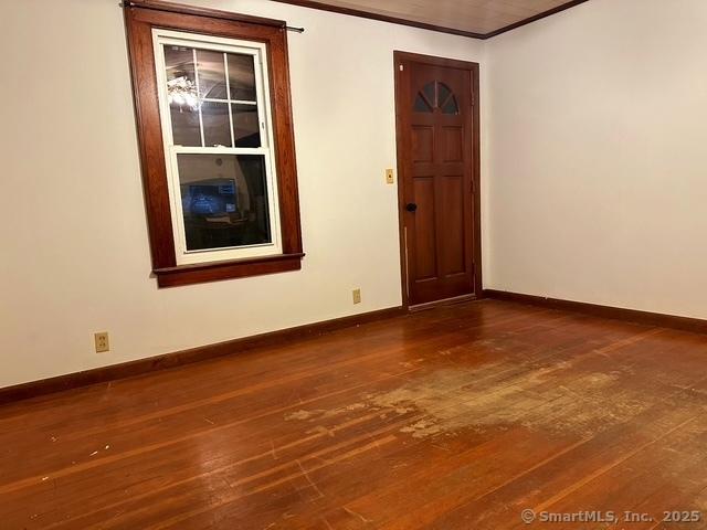 spare room with baseboards, dark wood finished floors, and crown molding