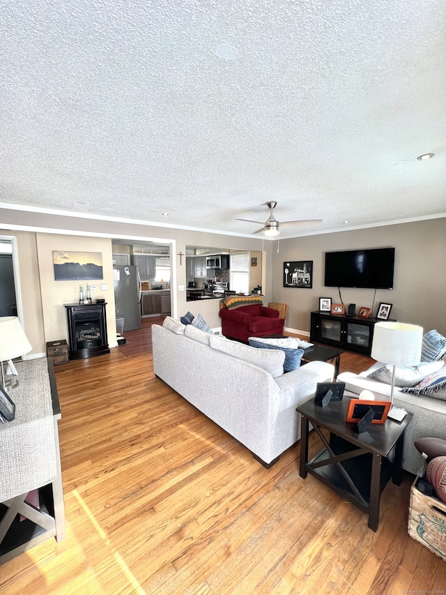 living room with hardwood / wood-style flooring, ceiling fan, crown molding, and a textured ceiling