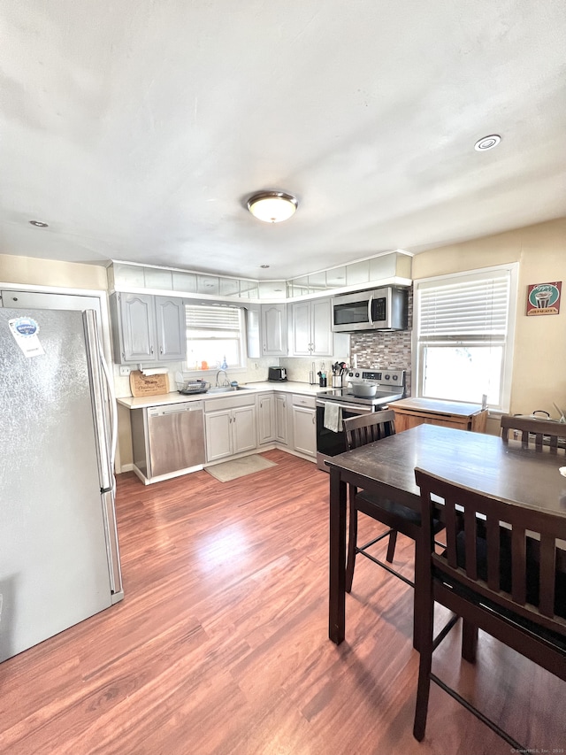 kitchen featuring sink, gray cabinets, stainless steel appliances, tasteful backsplash, and wood-type flooring