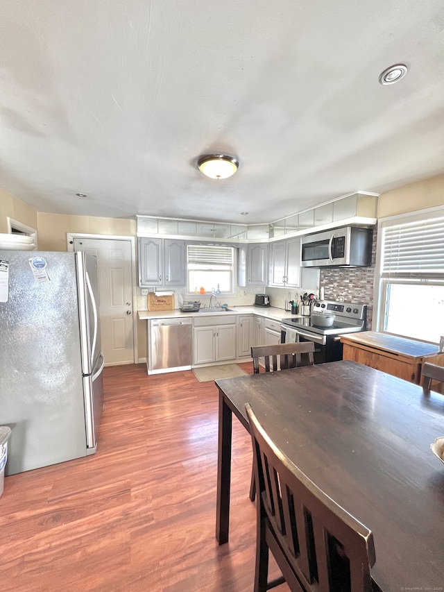 kitchen with gray cabinets, tasteful backsplash, sink, stainless steel appliances, and dark wood-type flooring