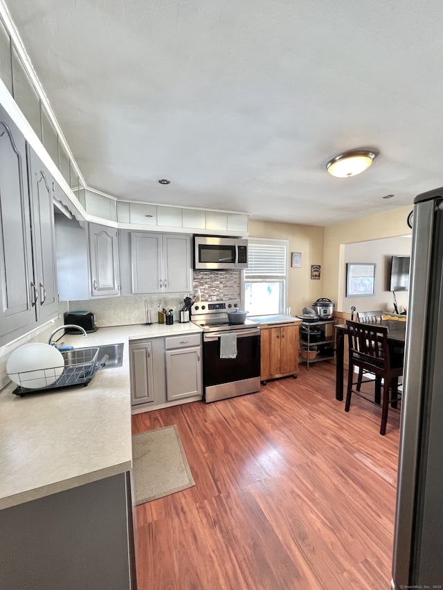 kitchen featuring sink, tasteful backsplash, dark hardwood / wood-style floors, gray cabinets, and stainless steel appliances