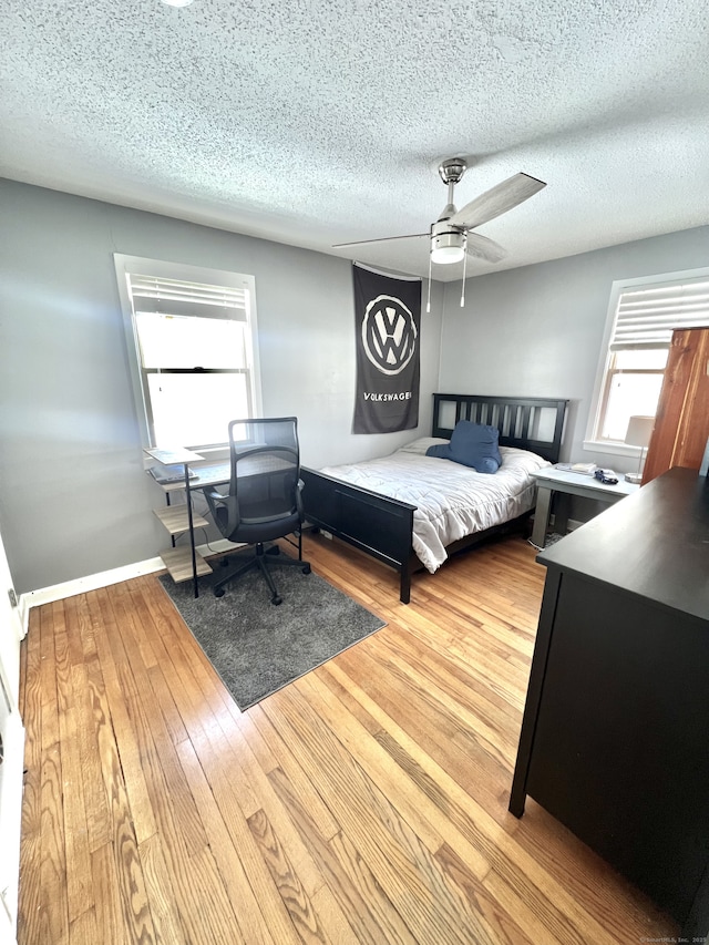 bedroom featuring ceiling fan, light hardwood / wood-style floors, and a textured ceiling