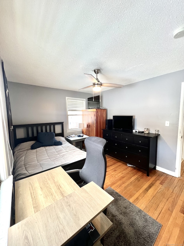 bedroom featuring ceiling fan, hardwood / wood-style flooring, and a textured ceiling