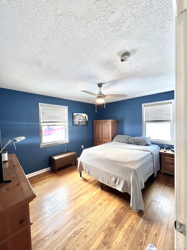 bedroom with a textured ceiling, light hardwood / wood-style flooring, and ceiling fan